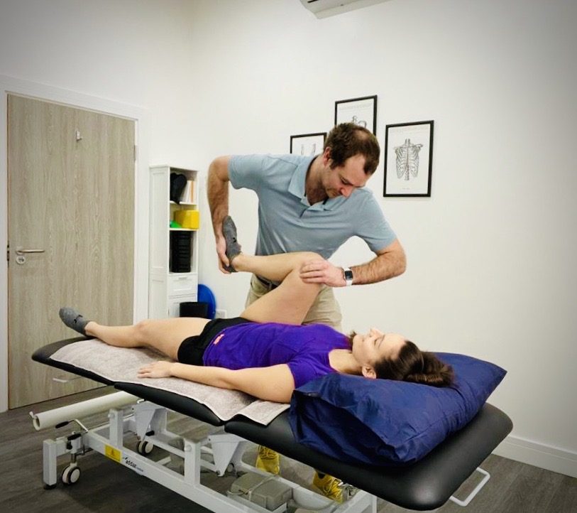 Physio assessing a patients hip on a treatment couch