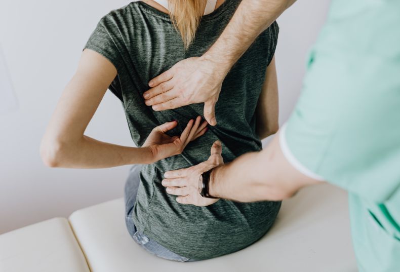 Physiotherapist assessing a patient’s lower back during a clinical examination
