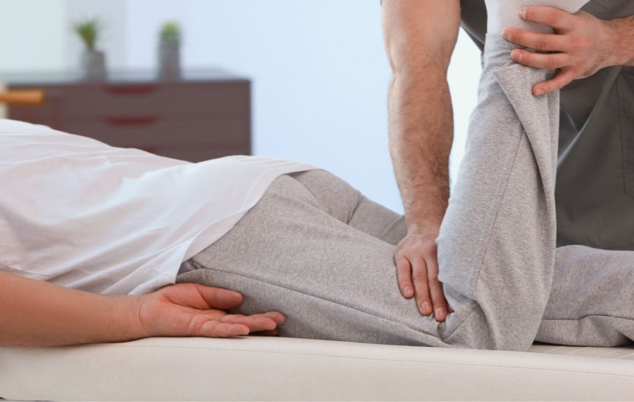 A physiotherapist bending the knee of a client