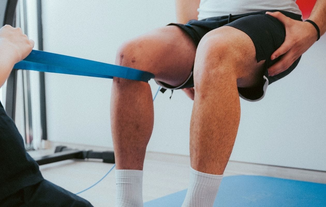 A physiotherapist using a resistance band on a person's knee