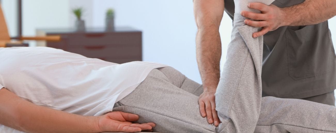 A physiotherapist bending the knee of a client