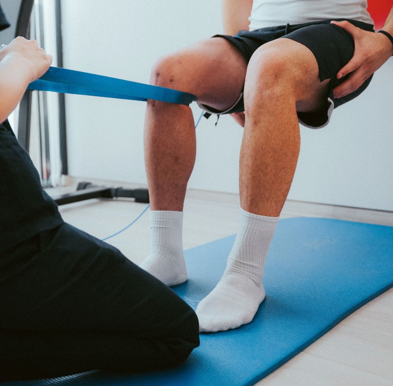 A physiotherapist using a resistance band on a person's knee