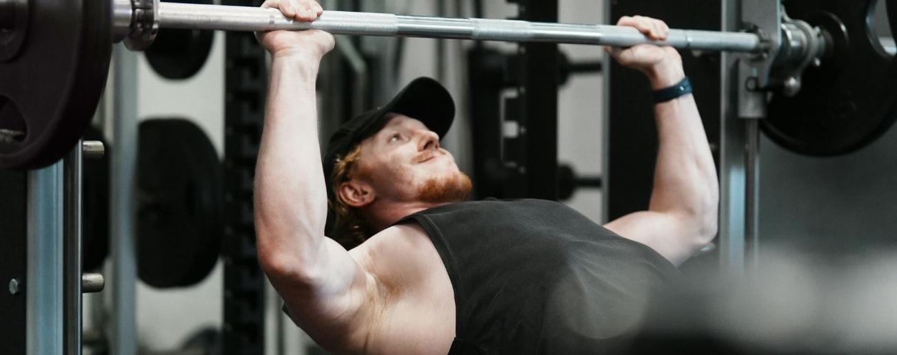 Man lifting a smith machine bar in a gym