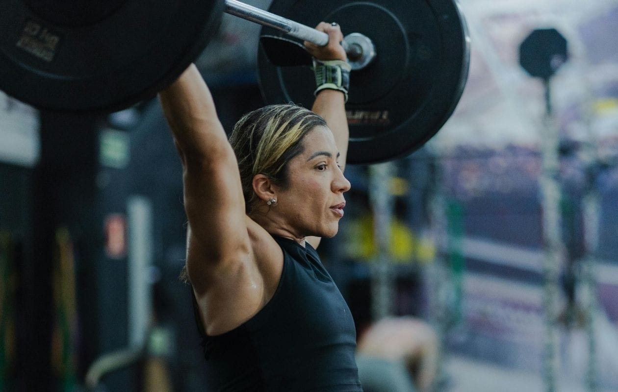 Female CrossFit athlete performing a barbell overhead press as part of a structured injury rehabilitation programme