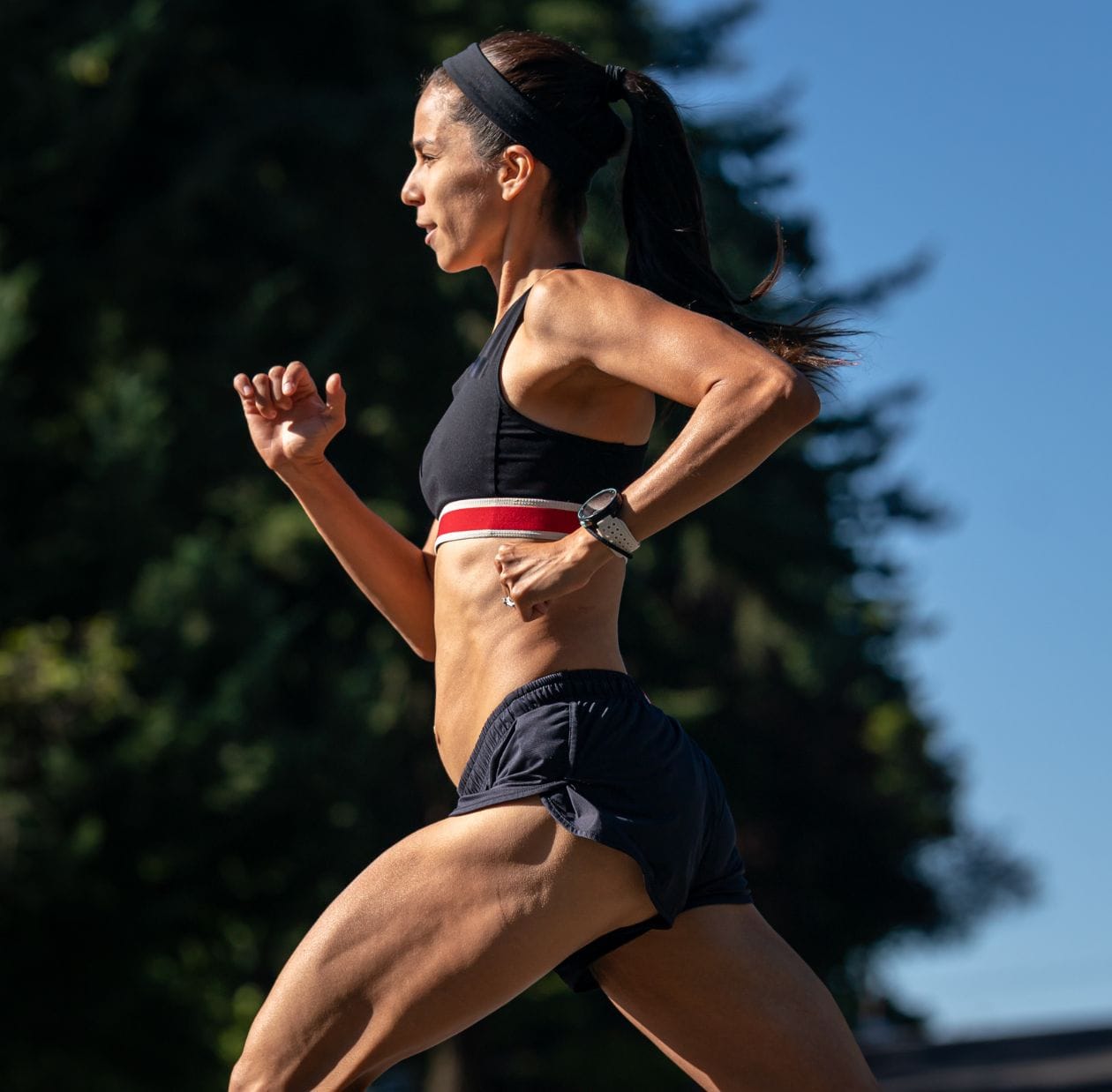Female runner in profile running outdoors on a sunny day, demonstrating a confident return to running after foot and ankle rehabilitation