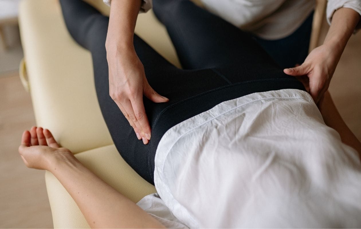 Physiotherapist assessing a patient's hip during a hands-on clinical examination on a treatment table