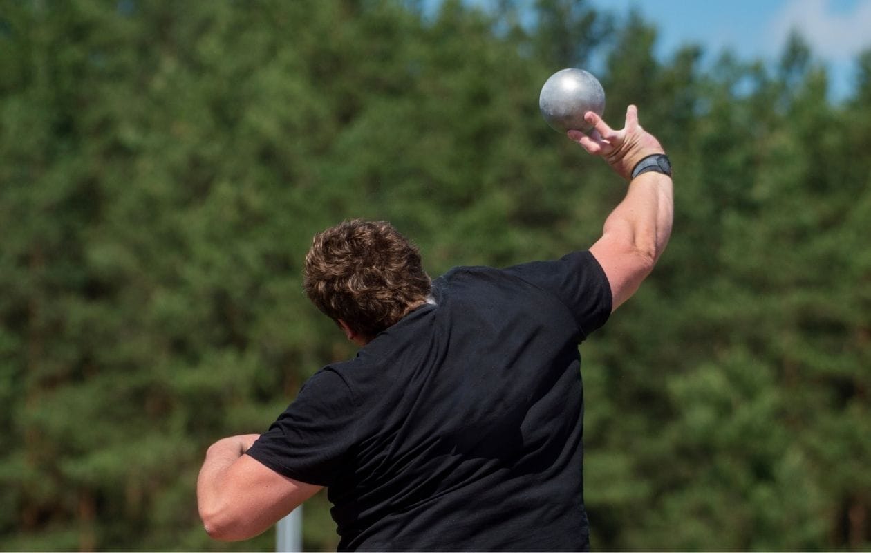 Male athlete reaching overhead to serve, demonstrating the throwing and overhead loading patterns linked to sports shoulder pain