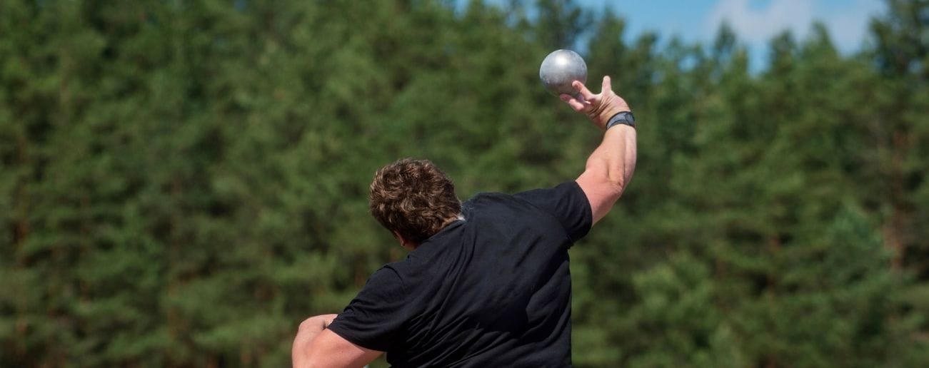 Male athlete reaching overhead to serve, demonstrating the throwing and overhead loading patterns linked to sports shoulder pain