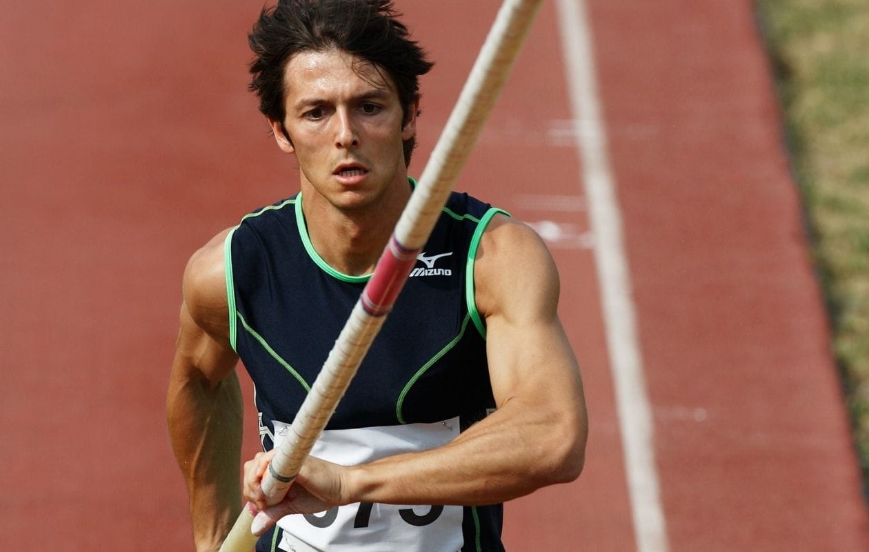 Male pole vaulter sprinting down the track carrying his pole, demonstrating a confident return to athletics after sports hip rehabilitation