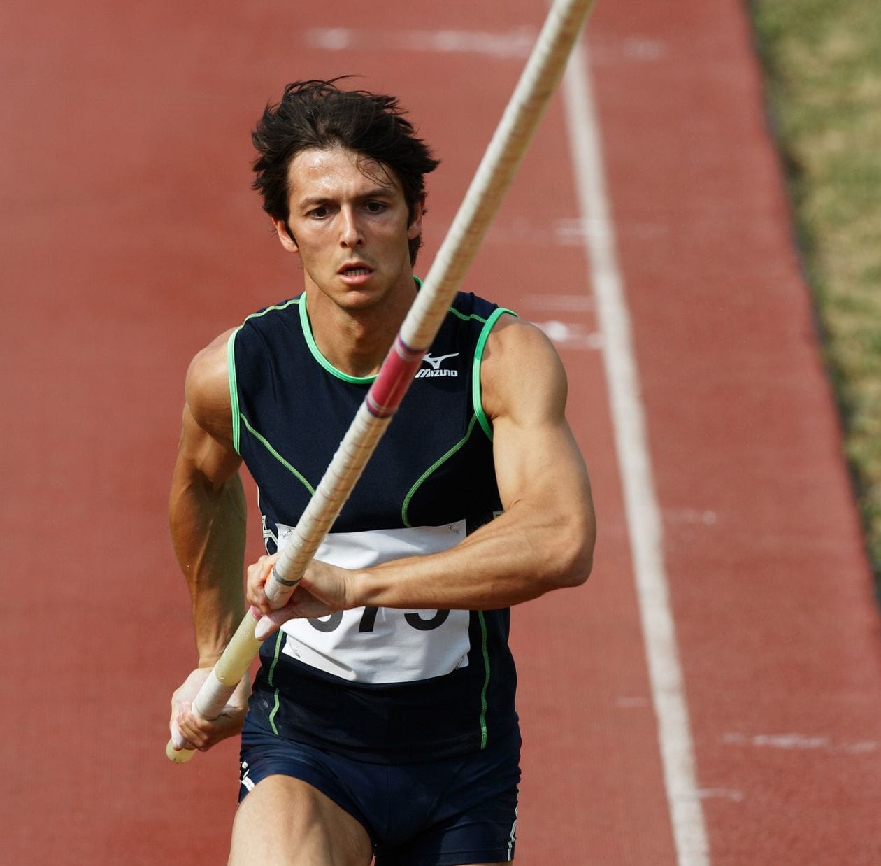 Male pole vaulter sprinting down the track carrying his pole, demonstrating a confident return to athletics after sports hip rehabilitation